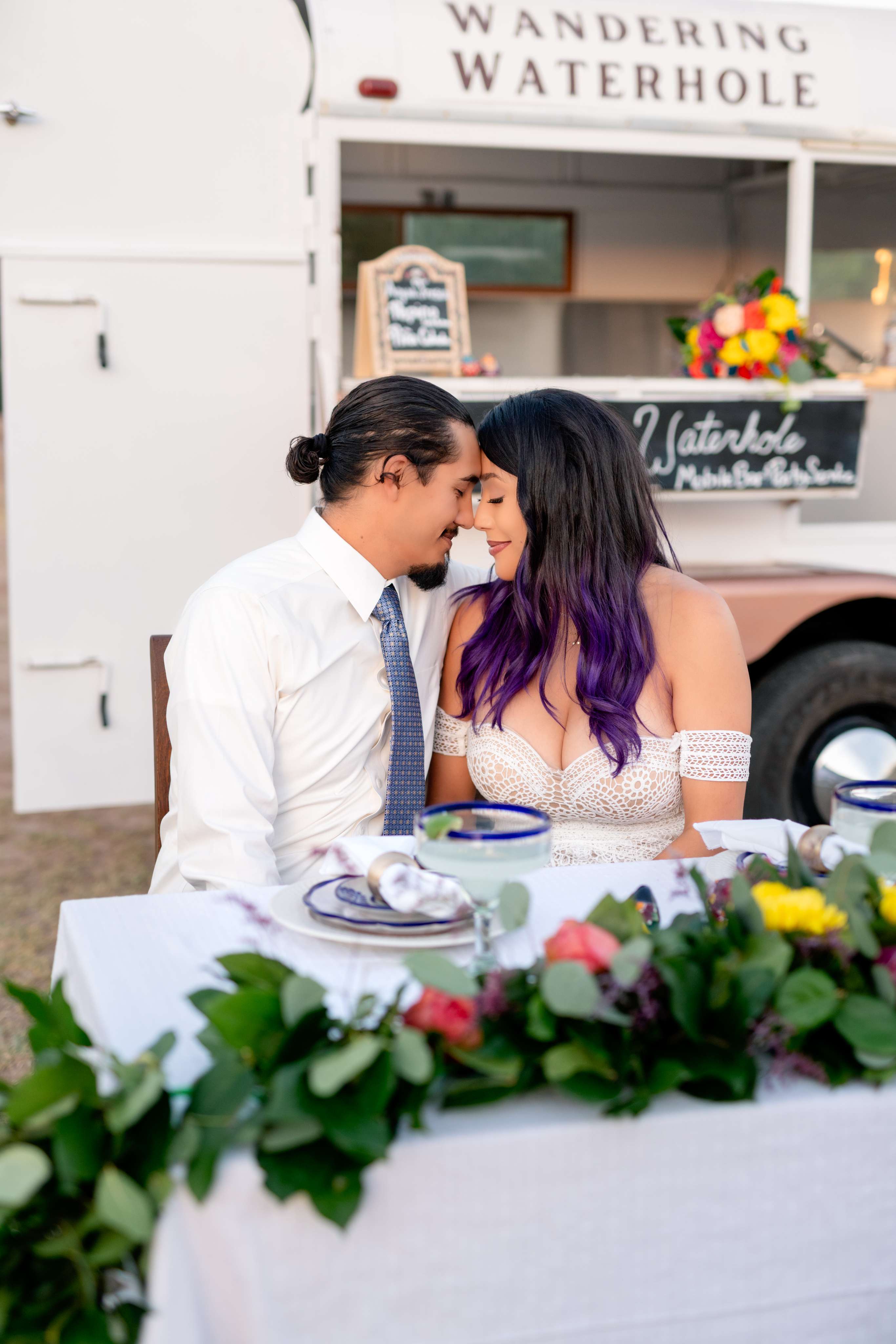 A man and a woman sitting at a table in front of a food truck